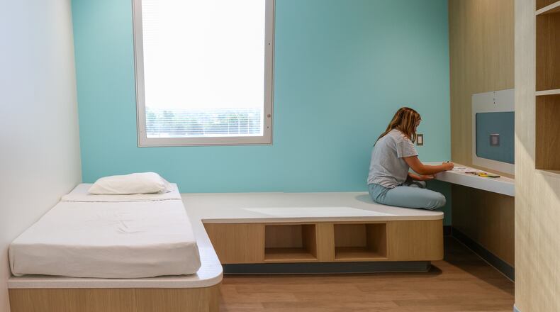 Eleanor Hake, an intern for Dayton Children's, colors while posing as a patient to demonstrate functionality in a room at Dayton Children's Mathile Center for Mental Health and Wellness during a tour on Monday June 9. The center will start serving patients in July. BRYANT BILLING / STAFF
