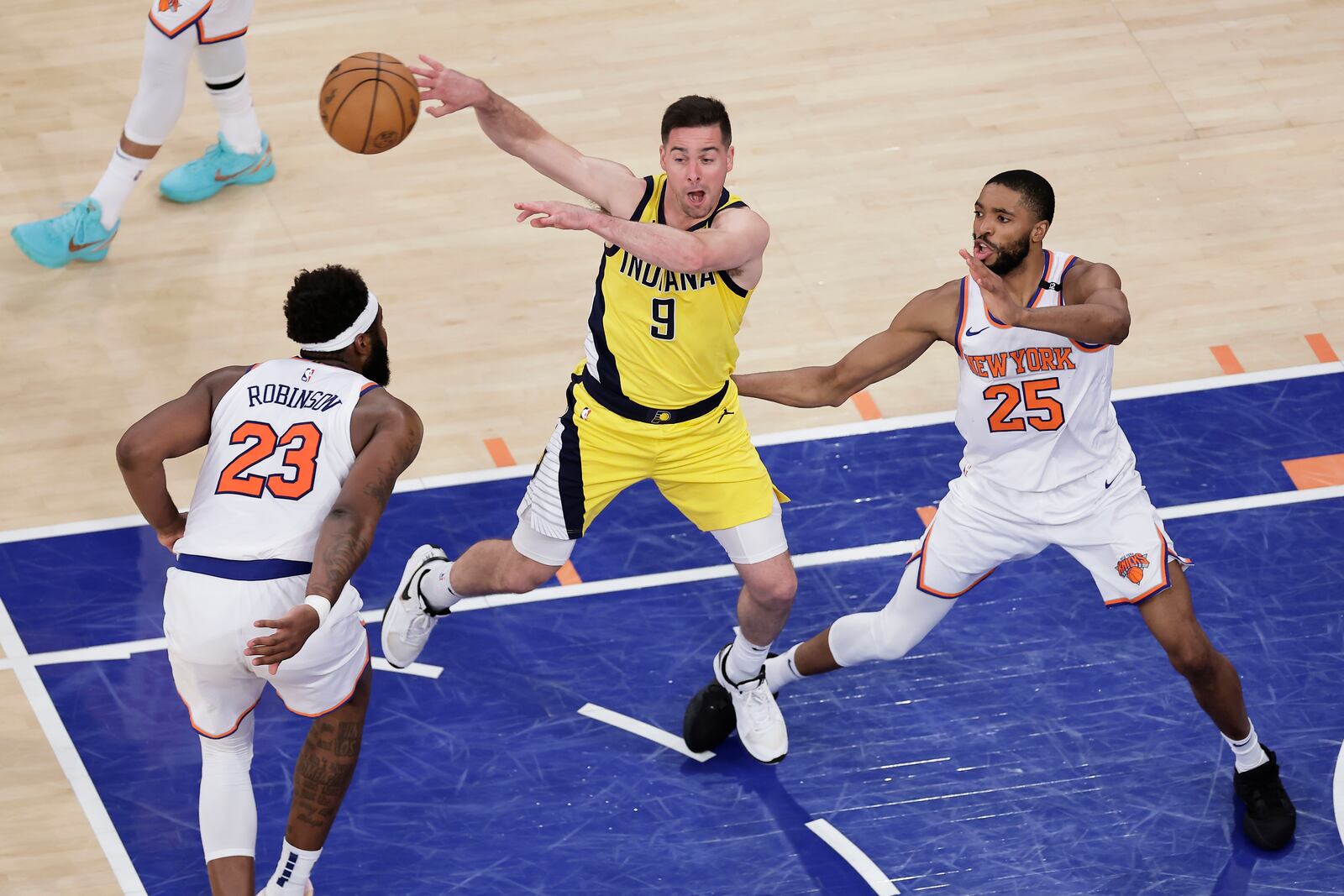 Indiana Pacers guard T.J. McConnell (9) passes the ball against New York Knicks center Mitchell Robinson (23) and forward Mikal Bridges (25) during the fourth quarter of Game 2 of the NBA basketball Eastern Conference final, Friday, May 23, 2025, in New York. (AP Photo/Adam Hunger)