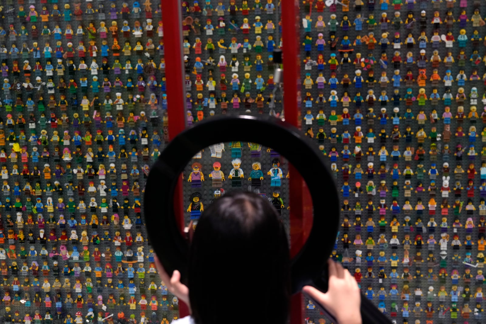 A child uses a magnifying glass to look at Lego characters at the hotel in Legoland Shanghai a day before it opens to the public in Shanghai, China, Friday, July 4, 2025. (AP Photo/Ng Han Guan)