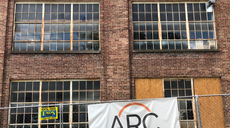 A sign for Alexander Recruiting hangs from a security fence around a former shoe factory the family has proposed for a $12 million redevelopment.