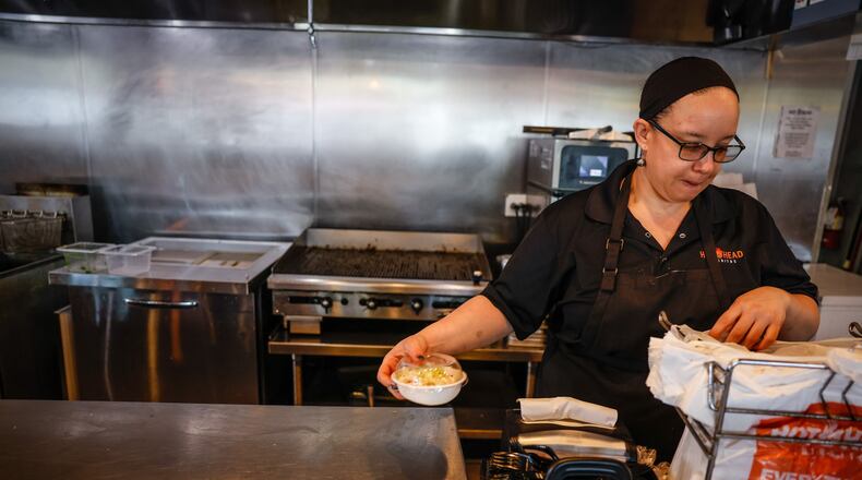 Manager of Hot Head Burritos on Brown St., Roxy Channels bags up food for a customer Monday June 13, 2022. JIM NOELKER/STAFF