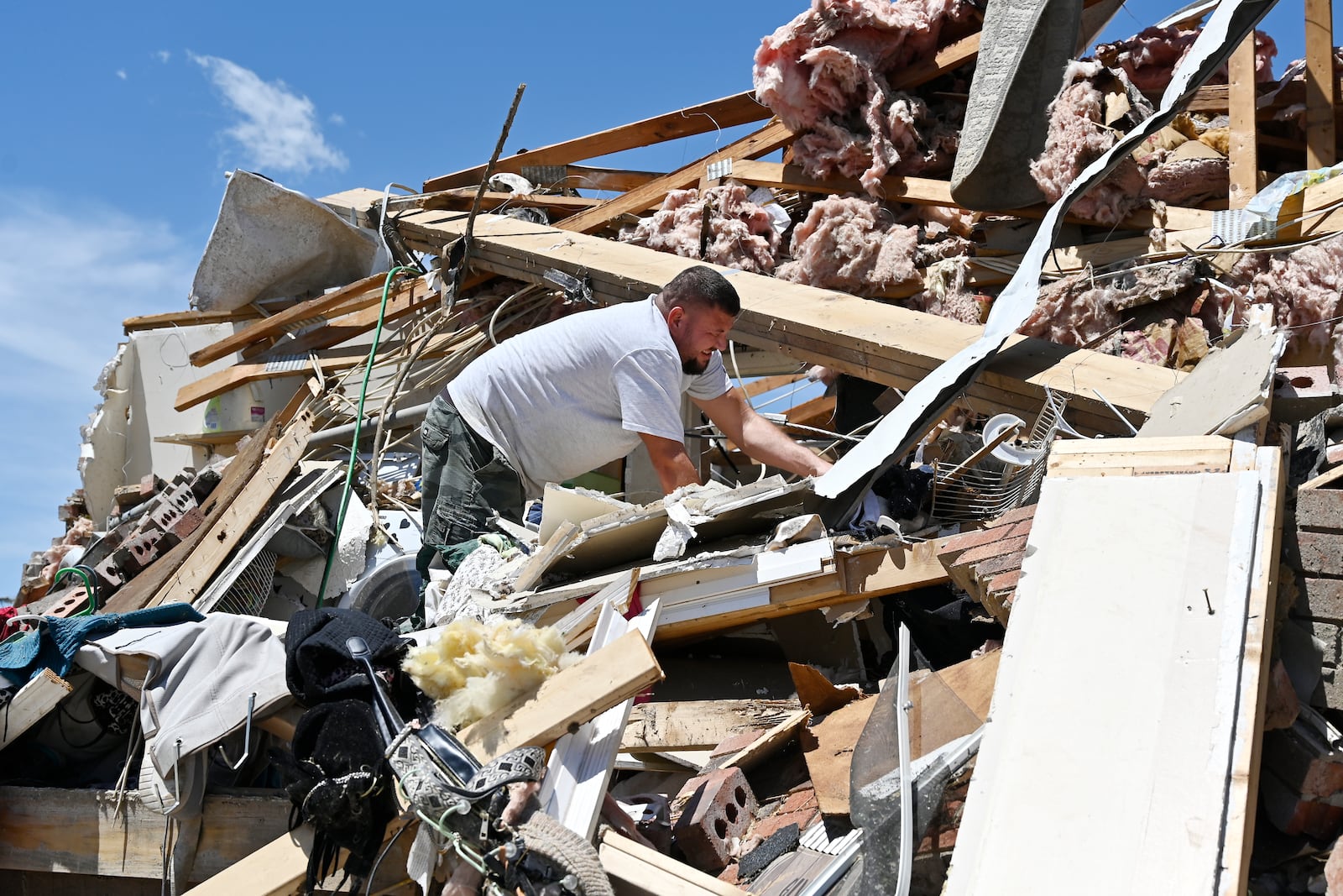 Anthony Broughton digs through the debris of his destroyed home following a severe storm in the Sunshine Hill neighborhood of London, Ky., Saturday, May 17, 2025. (AP Photo/Timothy D. Easley)