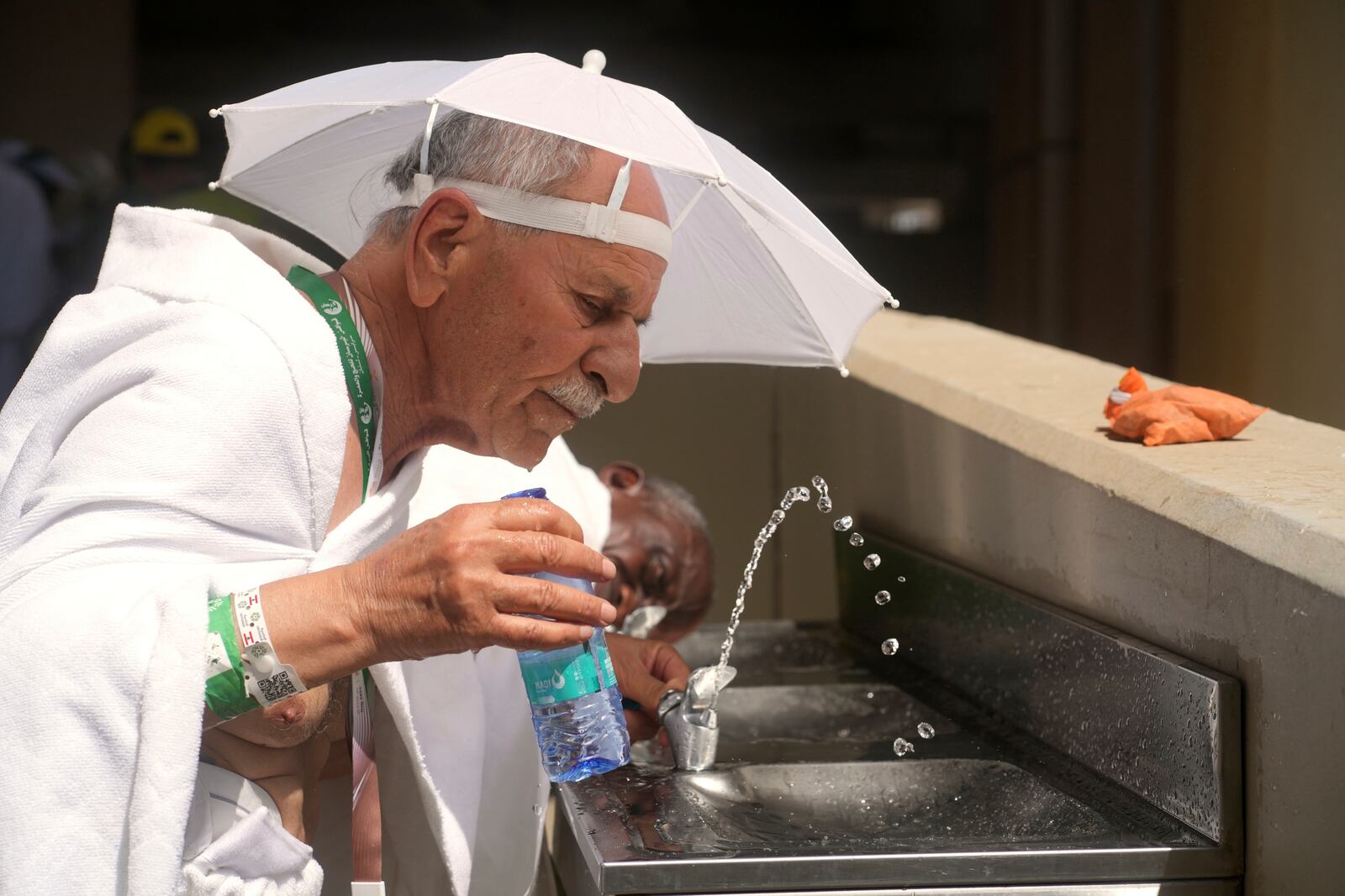 A Muslim pilgrim drinks water as he arrives to attend the symbolic stoning of the devil, the last rite of the annual Hajj, in Mina near the holy city of Mecca, Saudi Arabia, Friday, June 6, 2025. (AP Photo/Amr Nabil)