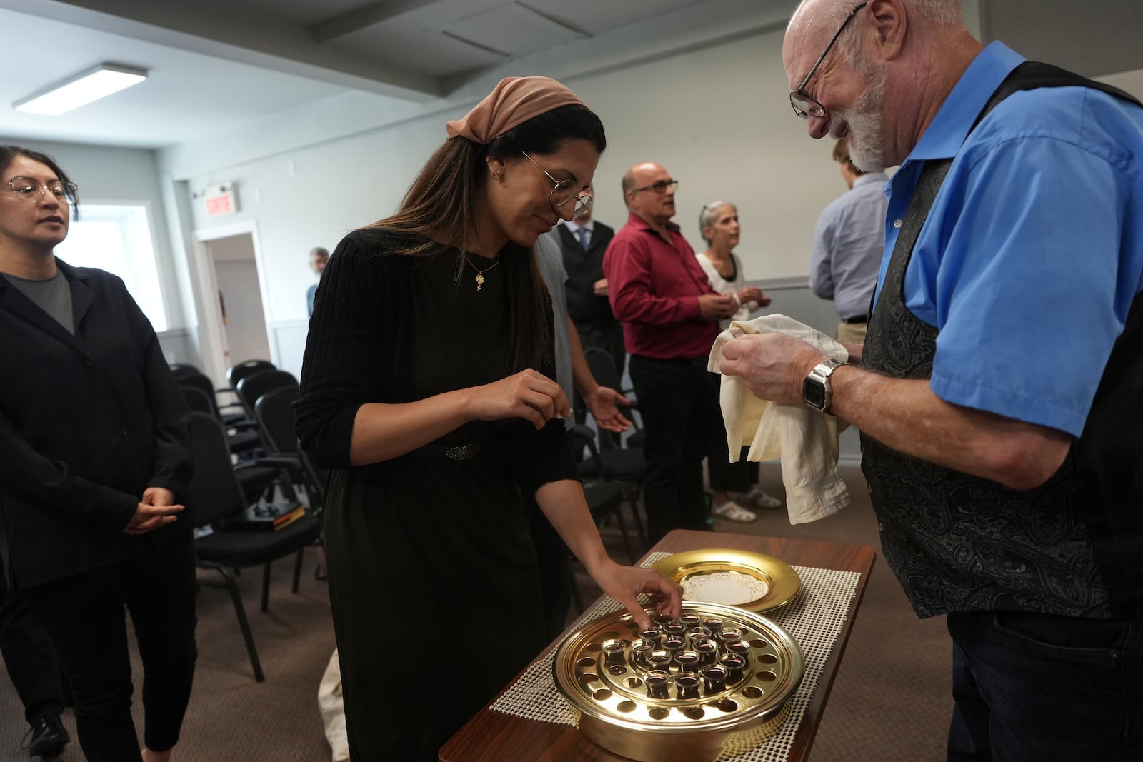 Megane Ares-Dube, center, prepares to receive communion during service at the Reformed Baptist Church in Saint Jerome, Quebec, Sunday, June 29, 2025. (AP Photo/Luis Andres Henao)