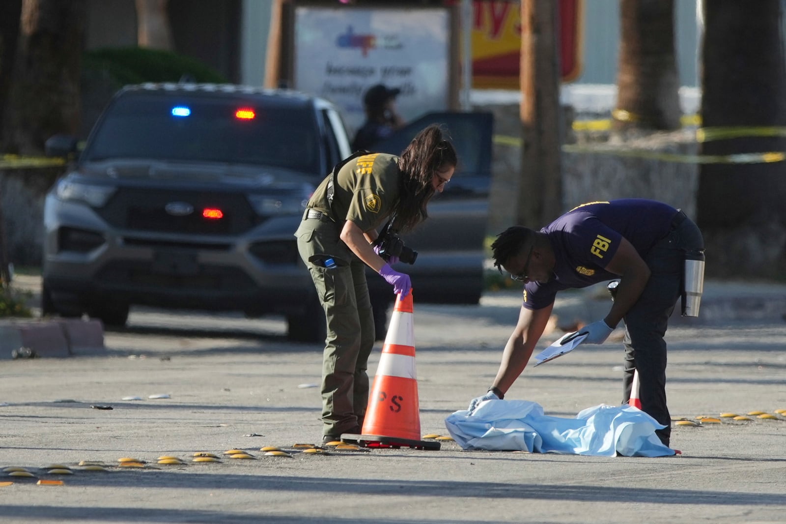 Investigators place a tarp over an item on a road near the site of an explosion in Palm Springs, Calif., on Saturday, May 17, 2025. (AP Photo/Eric Thayer)