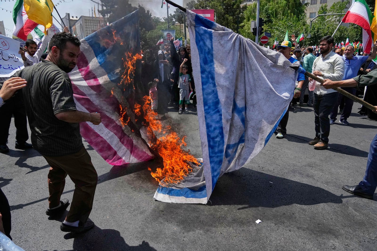 Iranian protestors burn representations of the Israeli and U.S. flags during a protest to condemn Israeli attacks on multiple cities across Iran, after the Friday prayers ceremony in Tehran, Iran, Friday, June 20, 2025. (AP Photo/Vahid Salemi)
