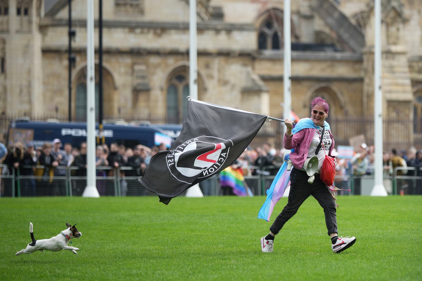 A person with a dog runs across Parliament Square as they take part in a rally organised by trans rights groups, trade unions, and community organisations following the Supreme Court ruling on the definition of a woman in equalities law, at Parliament Square, central London, Saturday April 19, 2025. (AP Photo/Alastair Grant)