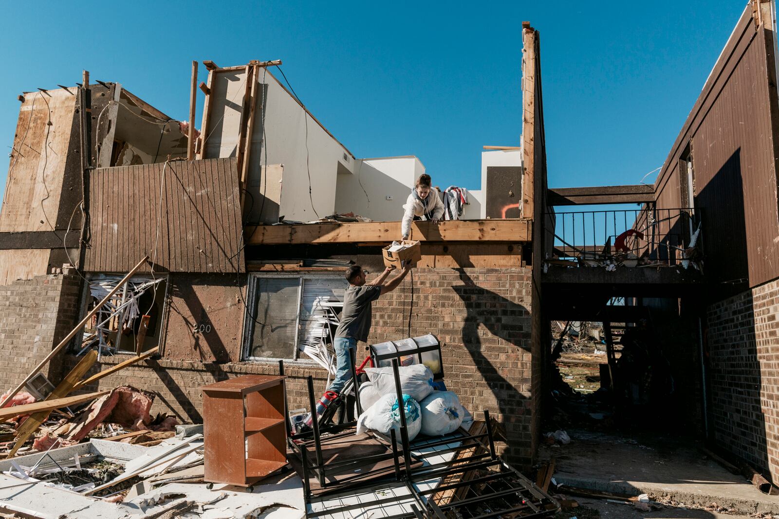 Joshua Joe Smith and one of his children Piper Smith, salvage items from their residence at the Dawson Village Apartments complex in Dawson Springs, Ky., on Monday, Dec. 13, 2021, where a tornado flattened much of the town on Friday night. Determining how many people died in the tornadoes that ravaged the central U.S. on Friday has been a challenging task so far, with estimates fluctuating as search teams continue to spread out amid vast fields of rubble in an effort to rescue the living and account for the dead. (William Widmer/The New York Times)