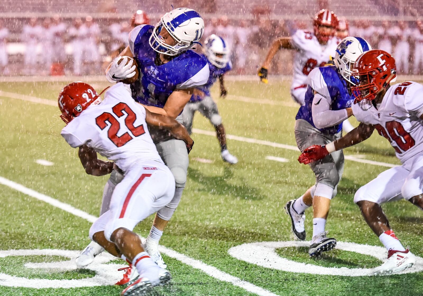 Fairfield’s Dealo McIntosh tackles Hamilton’s Luke Mattia in a driving rain Friday night at Virgil Schwarm Stadium in Hamilton. NICK GRAHAM/STAFF