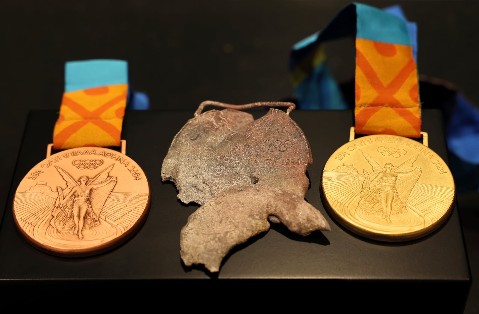 Two replica Olympic medals that IOC President Thomas Bach presented to American swimmer Gary Hall Jr. are seen alongside an original medal, that melted during the wildfires in Los Angeles that destroyed Hall's home earlier this year, during a ceremony at the Olympic House in Lausanne, Switzerland, Monday, May 5, 2025. (Denis Balibouse/Keystone/Reuters Pool via AP)