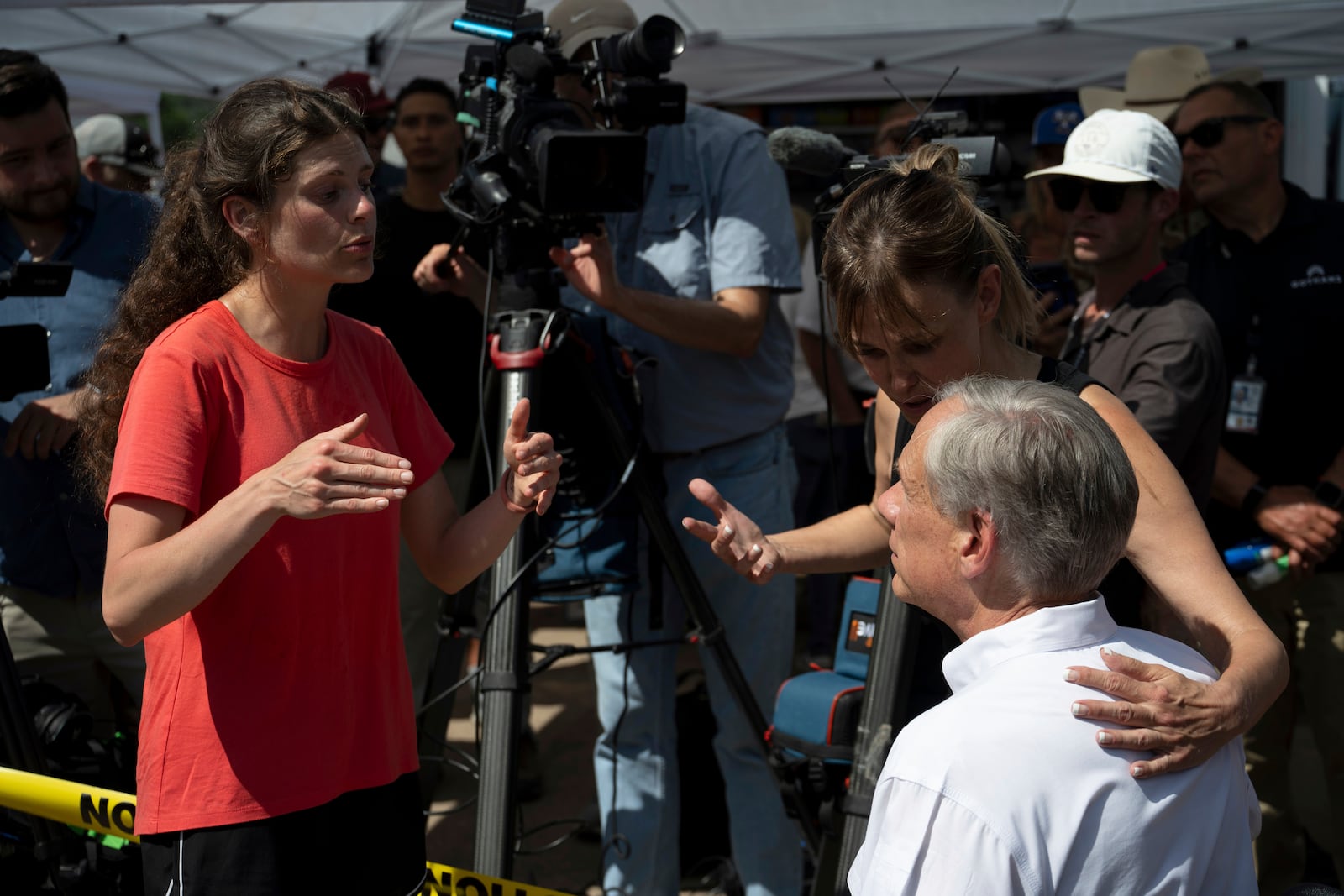 Courtney Calhoun, a resident in Kerr County, left, and Renee DeRese, top right, confront Texas Gov. Greg Abbott on Tuesday, July 8, 2025, in Hunt, Texas. (AP Photo/Eli Hartman)