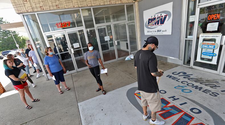 Dozens of people wait in line outside the Ohio Bureau of Motor Vehicles in the Southern Village Shopping Center in Springfield earlier this year after locations were reopened across the state. BILL LACKEY/STAFF