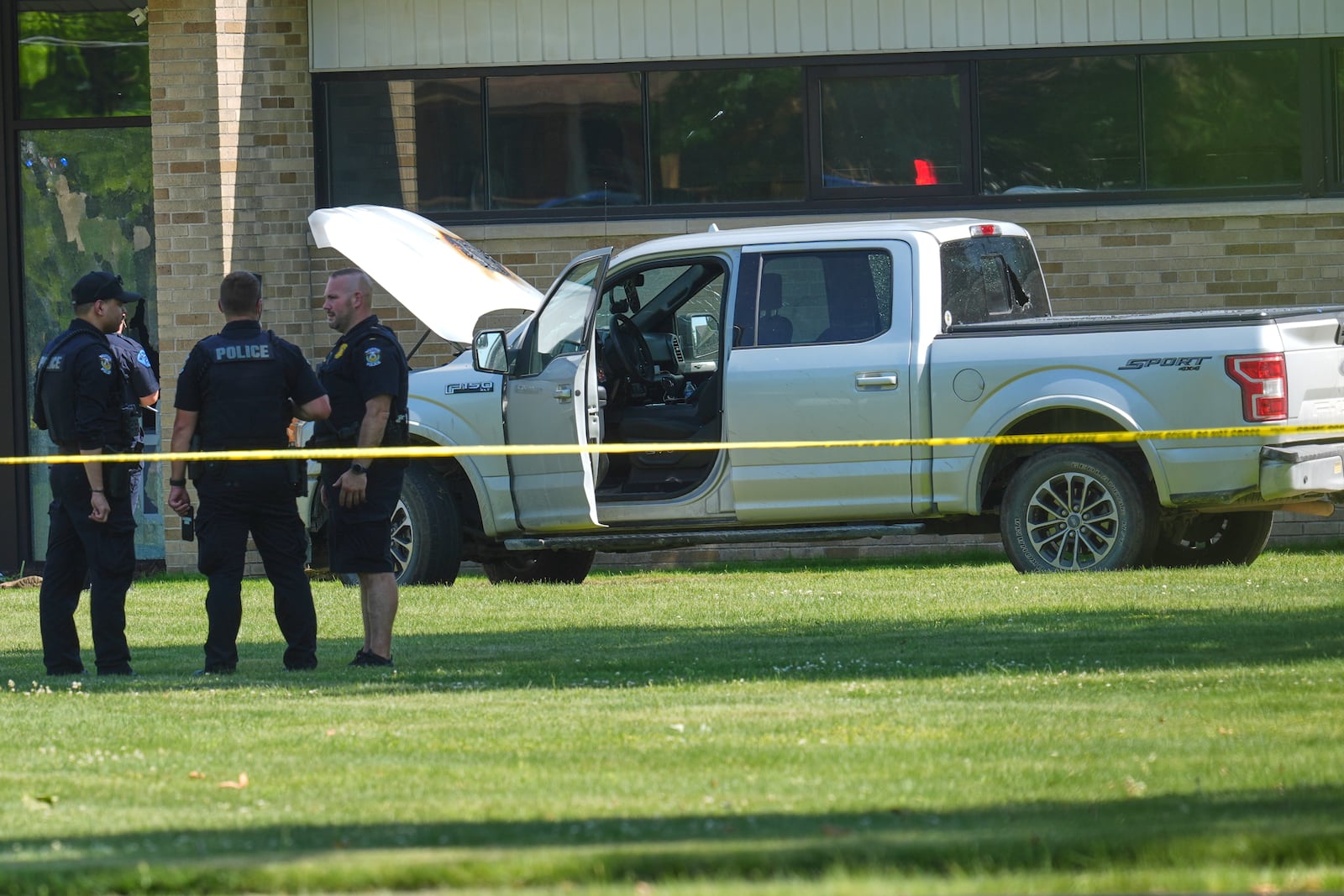 Police walk by an idle vehicle near CrossPointe Community Church in Wayne, Mich., Sunday, June 23, 2025. (AP Photo/Paul Sancya)