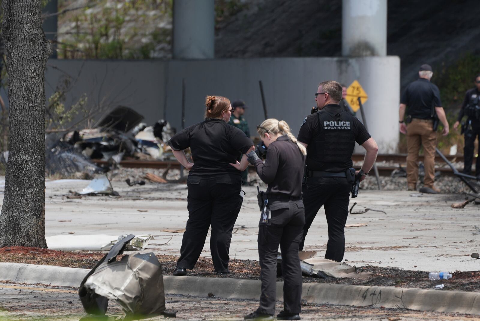 Emergency personnel respond to the area where a small plane crashed on the railroad tracks beneath the overpass near Interstate 95 in Boca Raton, Fla., on Friday, April 11, 2025. (AP Photo/Marta Lavandier)