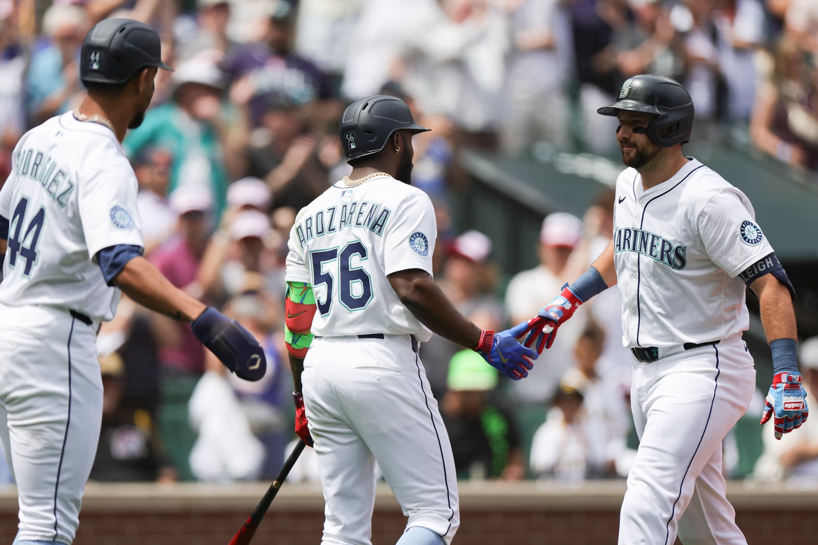 Seattle Mariners designated hitter Cal Raleigh, right, celebrates with Randy Arozarena, center, and Julio Rodriguez, left, after hitting a two-run home run during the first inning of a baseball game against the Pittsburgh Pirates, Friday, July 4, 2025, in Seattle. (AP Photo/Ryan Sun)