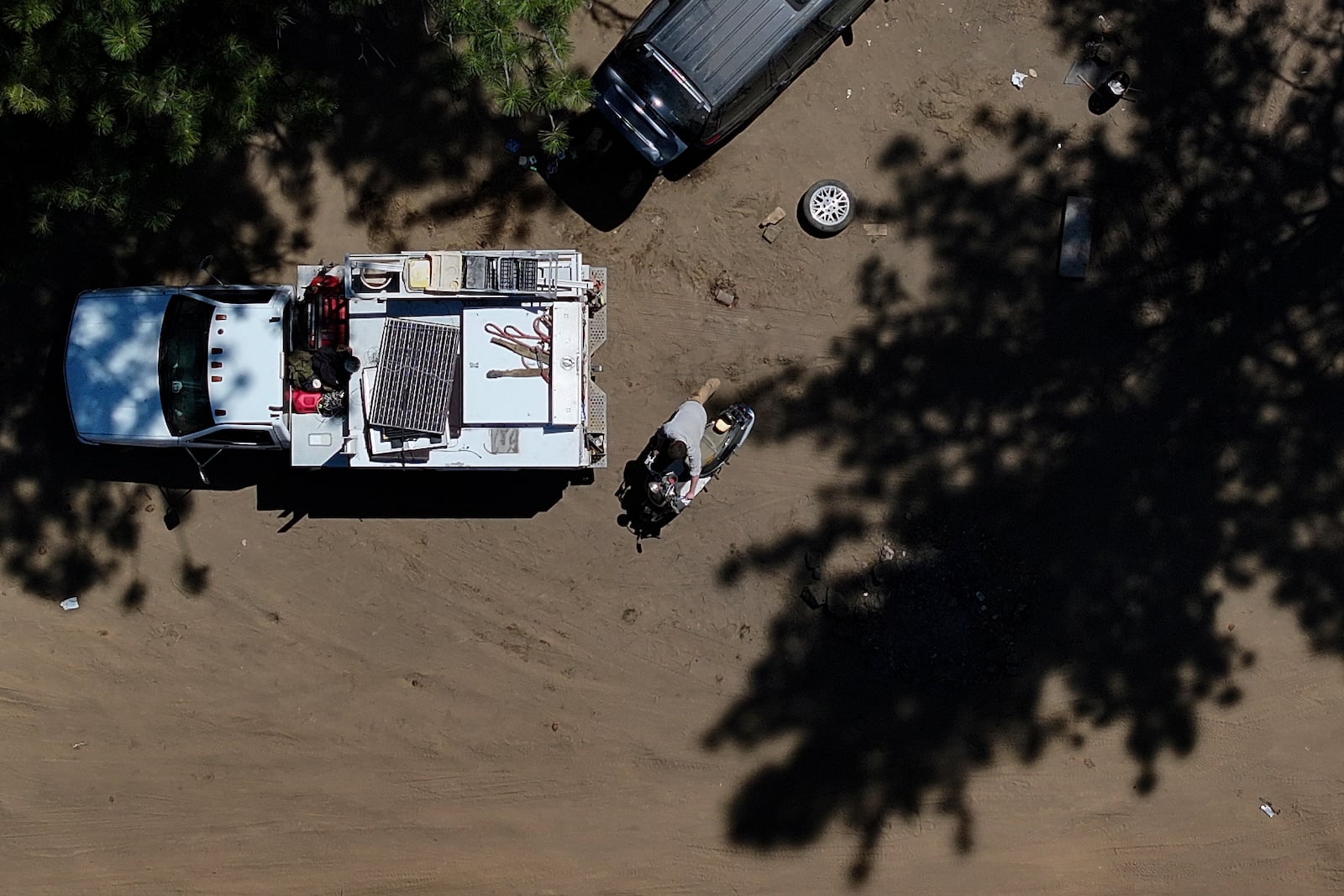 Chris Daggett, who lived in a homeless encampment in Deschutes National Forest, pushes a scooter belonging to another resident as he helps to remove items for fellow campers on Thursday, May 1, 2025, near Bend, Ore. (AP Photo/Jenny Kane)