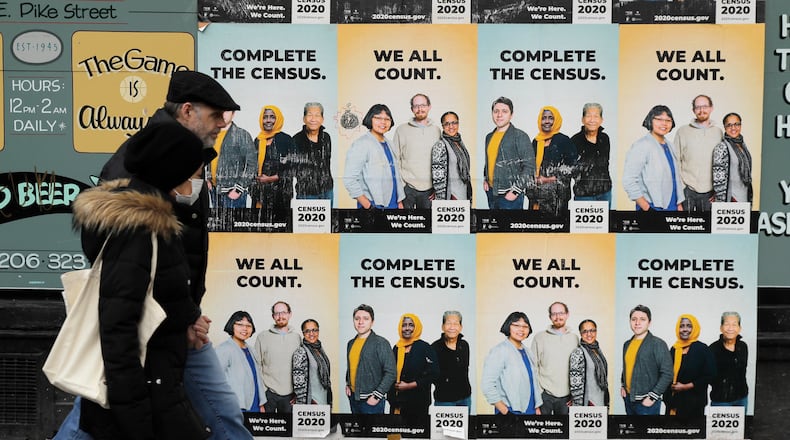 FILE - In this Wednesday, April 1, 2020 file photo,People walk past posters encouraging participation in the 2020 Census in Seattle's Capitol Hill neighborhood. (AP Photo/Ted S. Warren, File)