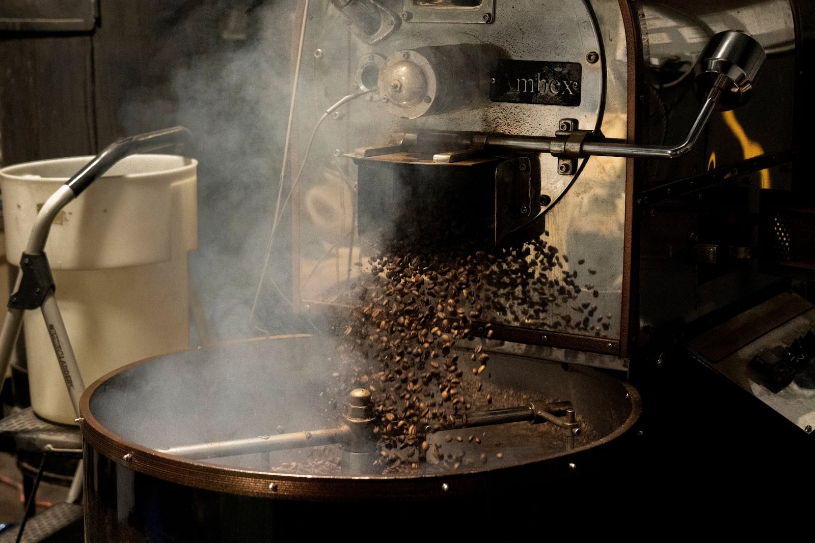Coffee beans fall into the cooling tray of a roasting machine at Fuego Coffee Roasters' roasting facility, Friday, March 21, 2025, in Rochester, N.Y. (Max Conway via AP)