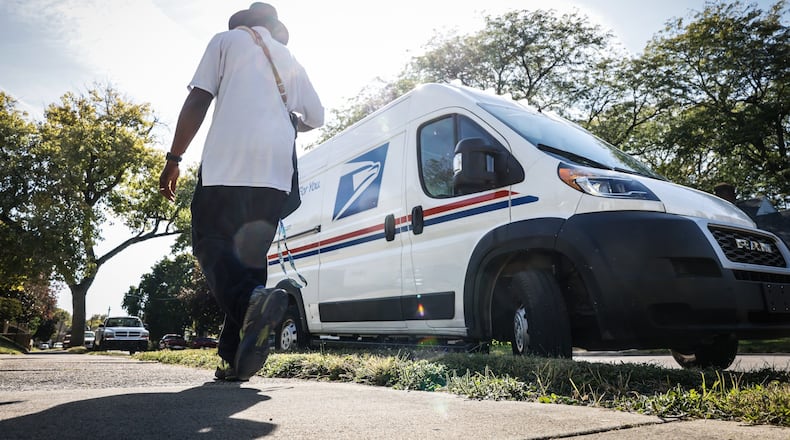 A mail carrier walks back to his truck after picking up and delivering mail on the eastside of Dayton. JIM NOELKER/STAFF
