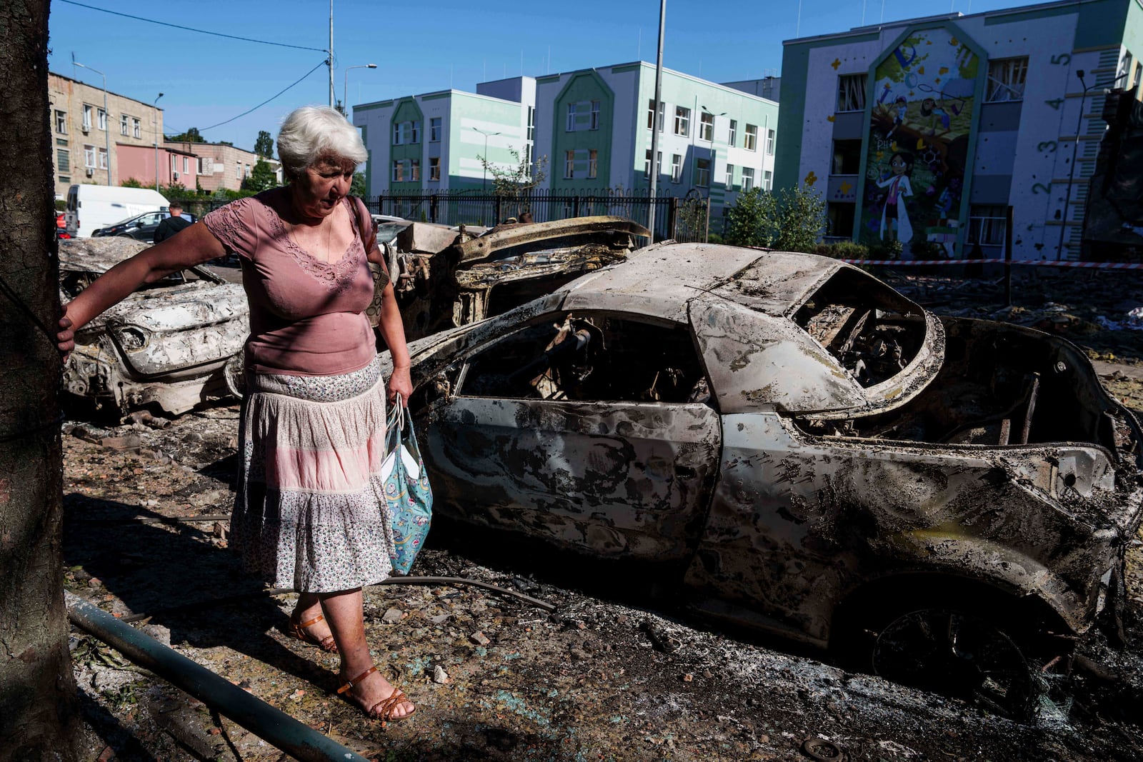 A local woman walks past cars destroyed by a Russian strike in Kyiv, Ukraine, on Friday, July 4, 2025. (AP Photo/Evgeniy Maloletka)