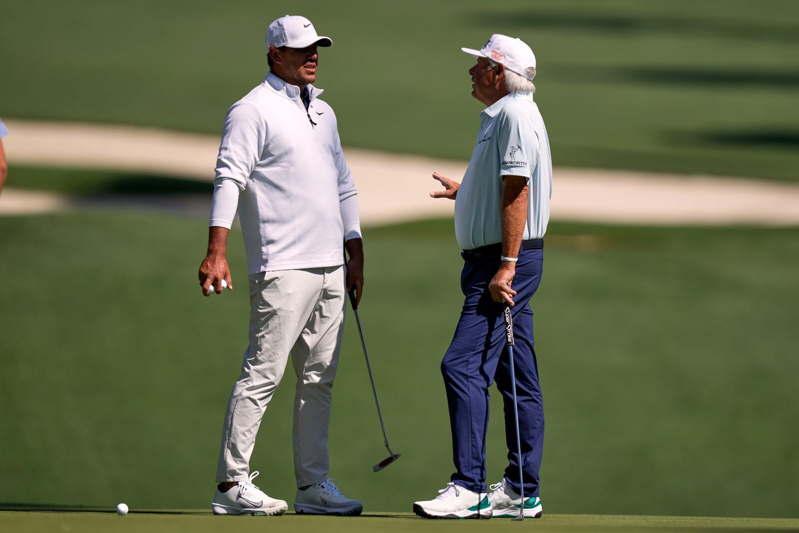 Brooks Koepka, left, talks with Fred Couples on the 10th green during a practice round at the Masters golf tournament, Tuesday, April 8, 2025, in Augusta, Ga. (AP Photo/Matt Slocum)