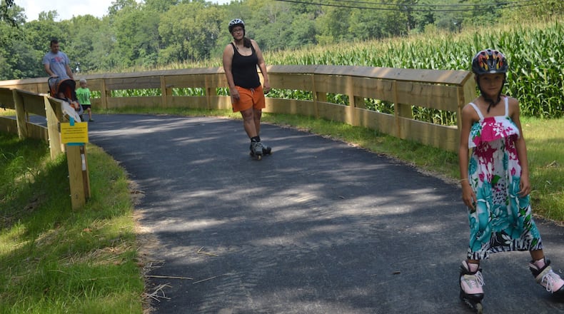 Madison Sparks, right, is followed by her mother, Megan, on the recently-opened section of the Oxford Recreational Trail leaving the Black Covered Bridge. Bill Sparks is at left with a stroller carrying Olivia and holding the hand of Sam. CONTRIBUTED/BOB RATTERMAN