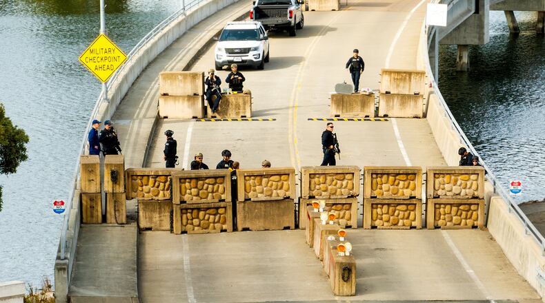 Coast Guardsmen stand watch behind a barrier at Coast Guard Base Alameda on Friday, Oct. 24, 2025, in Oakland, Calif. The barrier was erected earlier in the day after law enforcement officers fired on a vehicle as it backed towards them. (AP Photo/Noah Berger)