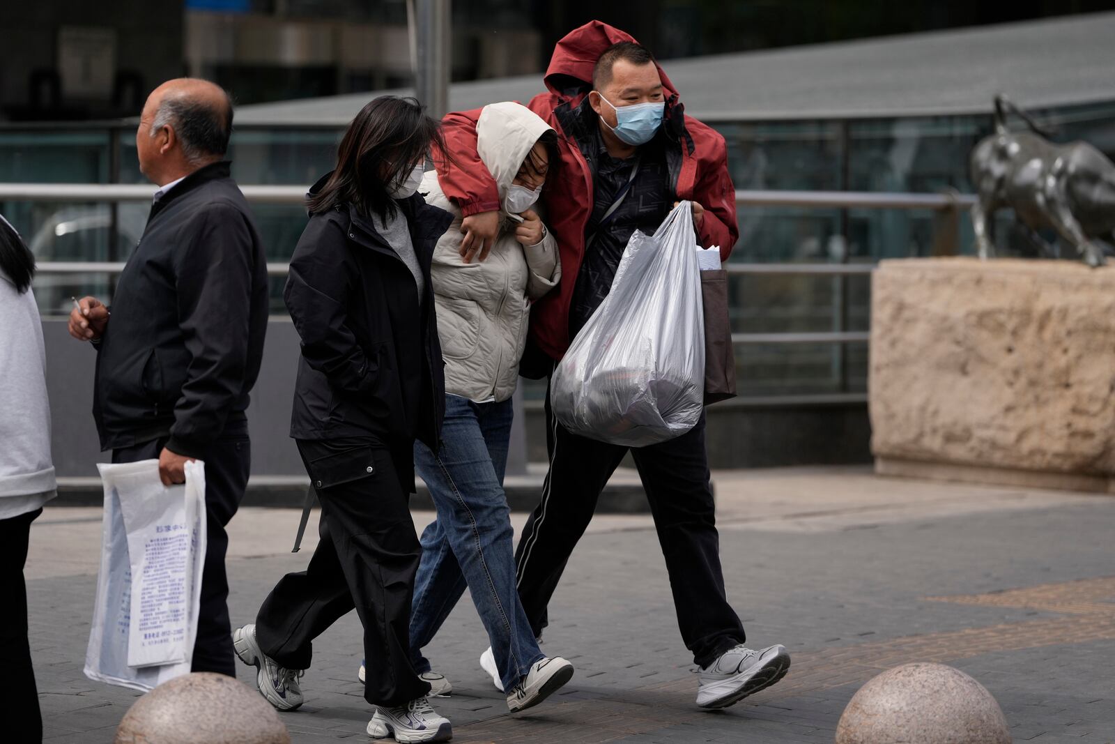 Residents walk against strong winds in Beijing, China, Saturday, April 12, 2025. (AP Photo/Ng Han Guan)