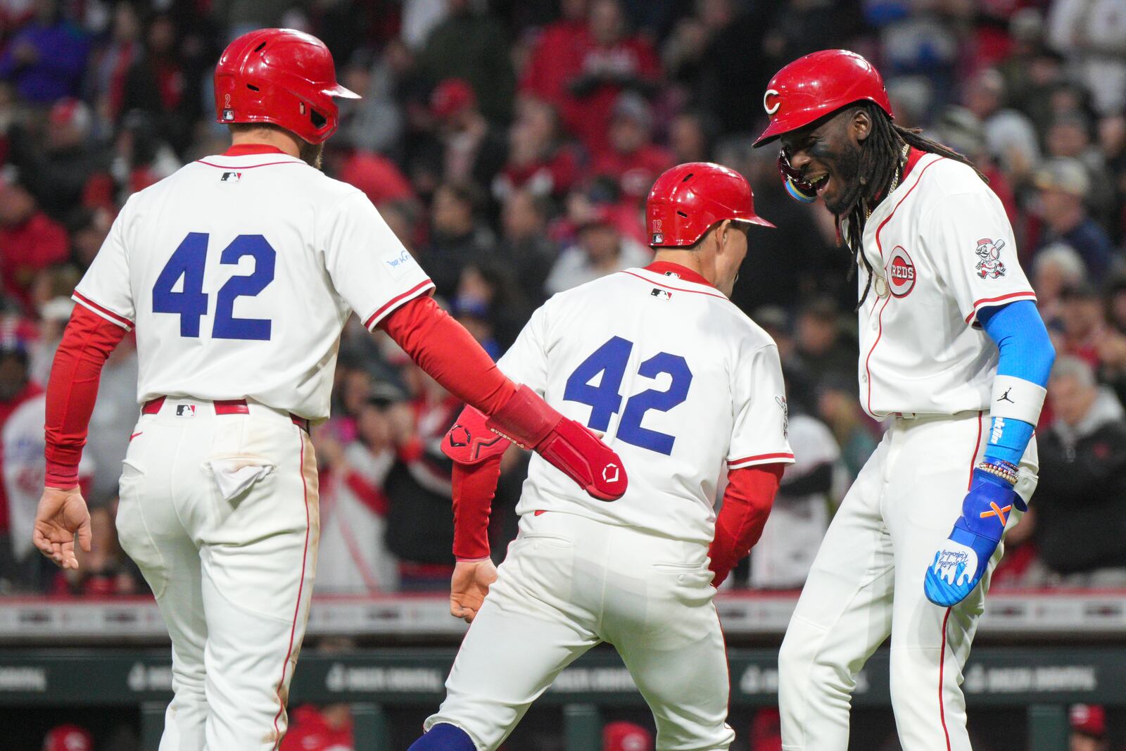 Cincinnati Reds' Austin Hays, center, celebrates with teammates Elly De La Cruz, right, and Gavin Lux after hitting g a three-run home run during the fifth inning of a baseball game against the Seattle Mariners, Tuesday, April 15, 2025, in Cincinnati. All the players are wearing 42 in honor of Jackie Robinson Day. (AP Photo/Jeff Dean)