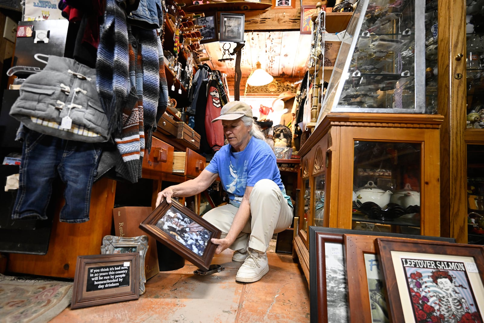 Tracy Turner, owner of the Wynola Junction, looks over pictures that fell from shelves when a earthquake hit Monday, April 14, 2025, in Julian, Calif. (AP Photo/Denis Poroy)