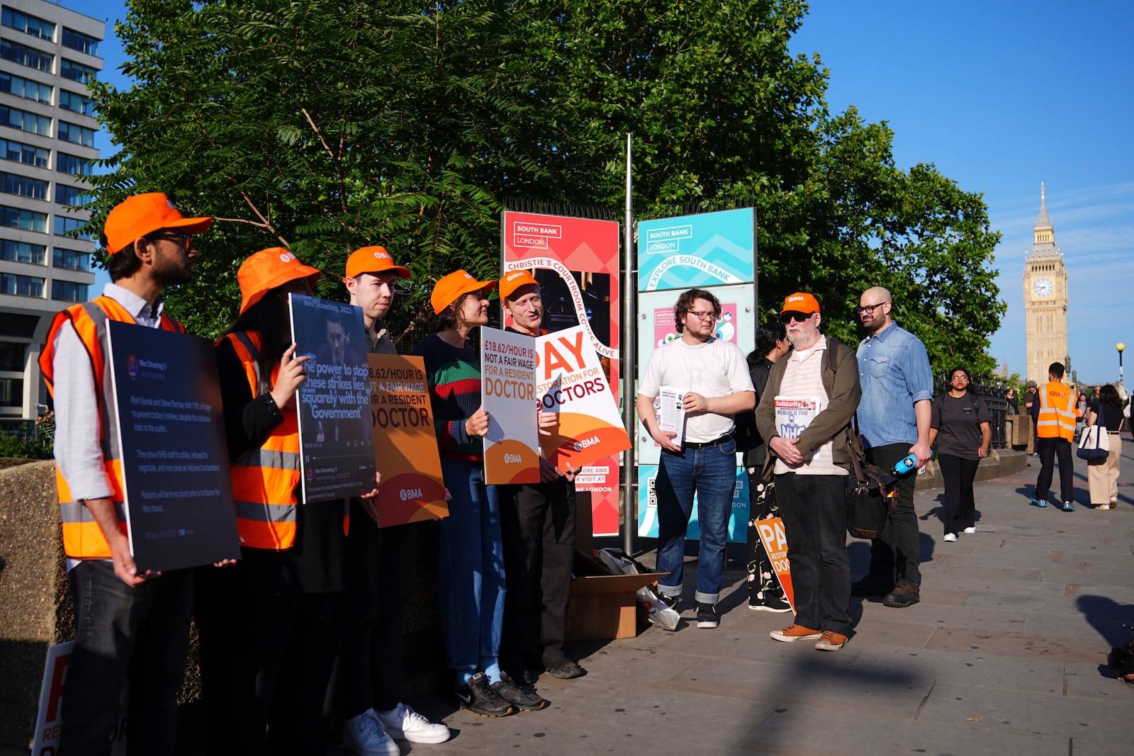 NHS resident doctors hold placards outside St Thomas' Hospital in London, as resident doctors in England, formerly referred to as junior doctors, begin a five-day strike after talks with the government collapsed over pay, Friday, July 25, 2025. ( James Manning/PA via AP)