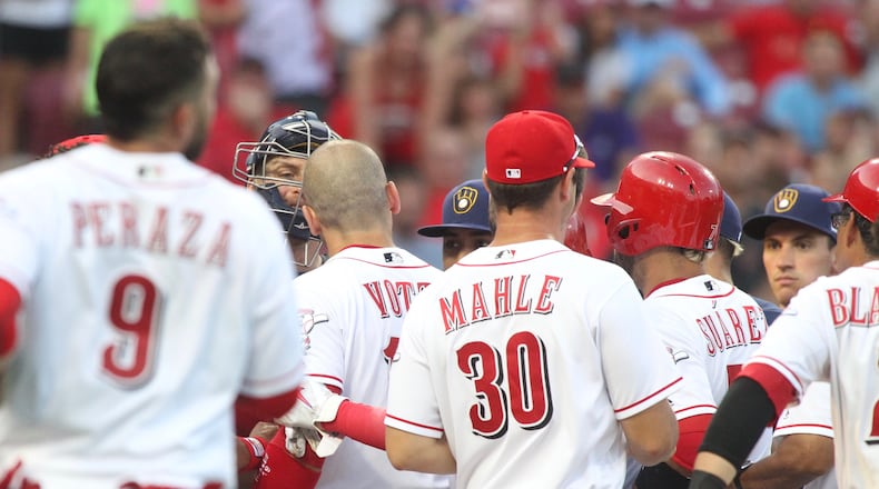 The Reds’ Joey Votto and Brewers catcher Erik Kratz exchange words at home plate in the third inning on Thursday, June 28, 2018, at Great American Ball Park in Cincinnati. David Jablonski/Staff