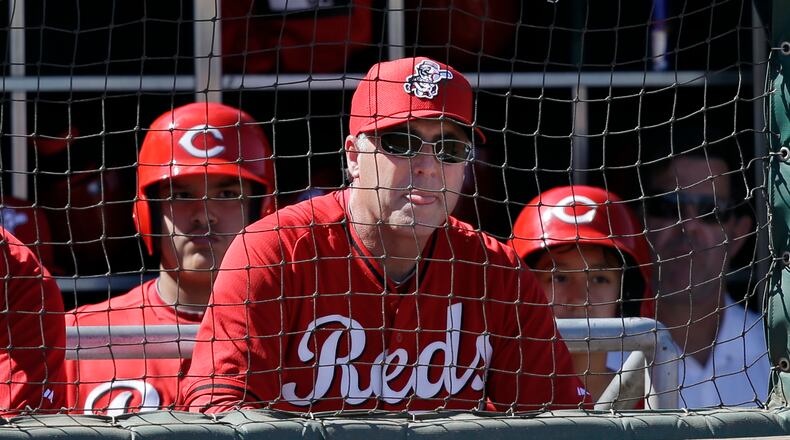 Cincinnati Reds manager Bryan Price, center, watches from the dugout in the second inning of a spring training exhibition baseball game against the Chicago Cubs Saturday, March 8, 2014, in Goodyear, Ariz. (AP Photo/Mark Duncan)