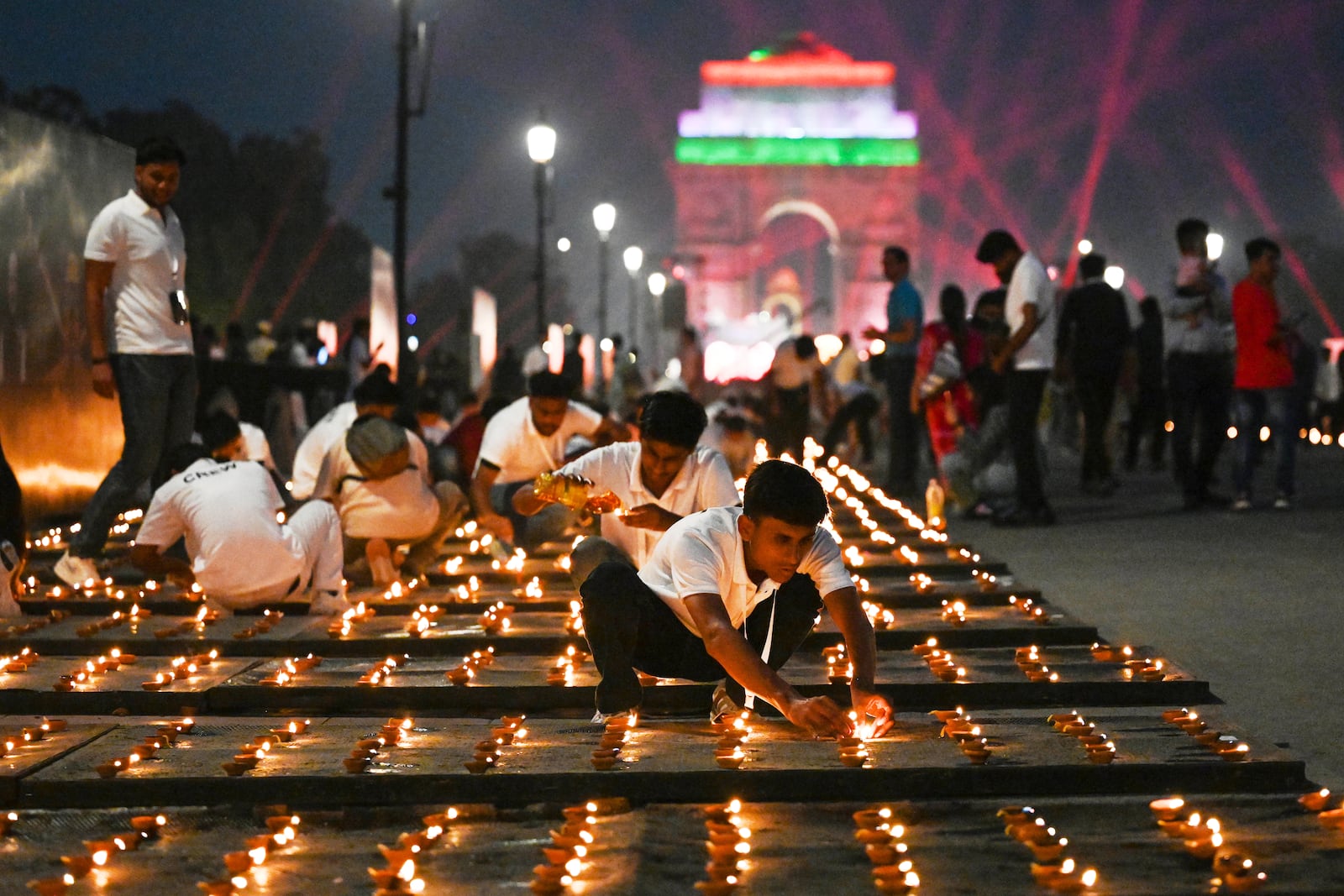 Volunteers light rows of lamps on Kartavya Path near India Gate as part of the Delhi government's Diwali celebrations in New Delhi, India, Saturday, Oct. 18, 2025. (AP Photo/Deepanshu Aggarwal)