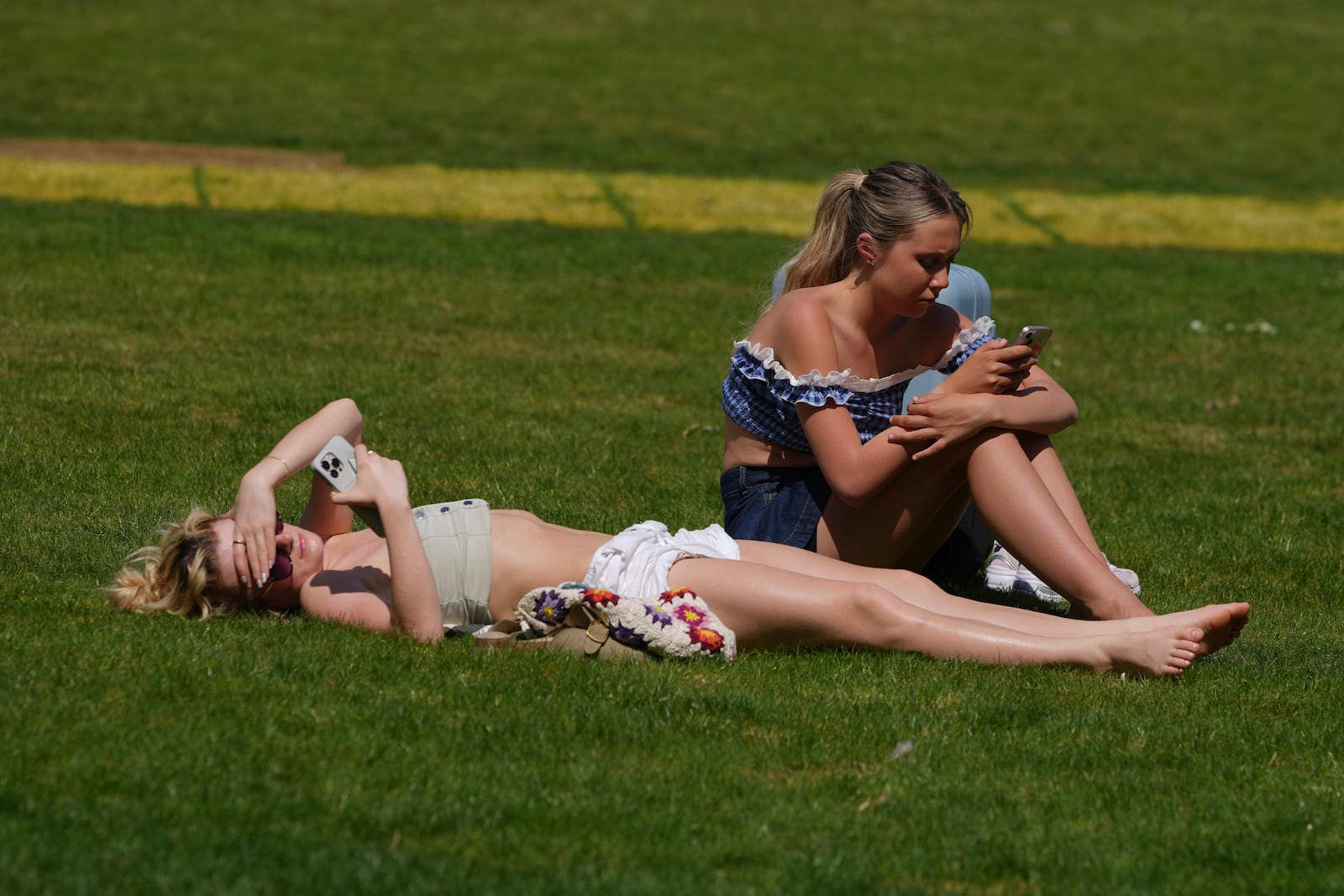 People sunbathe on a sunny day at a park in London, Wednesday, April 30, 2025. (AP Photo/Kin Cheung)