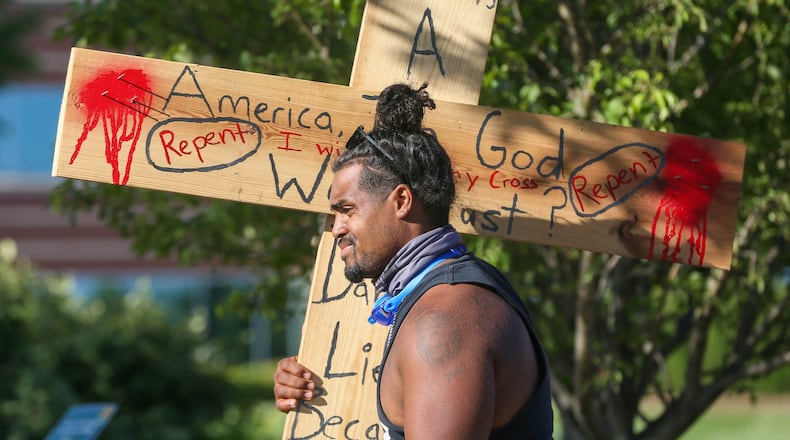 Protesters like Denorver Garrett, 28, formerly of West Chester, gathered at the West Chester Clock Tower Tuesday for a peaceful event that included chants and speakers as protests continue throughout the region after the of a Minnesota man in police custody. He carried a large, wooden cross from his truck to the event. GREG LYNCH / STAFF