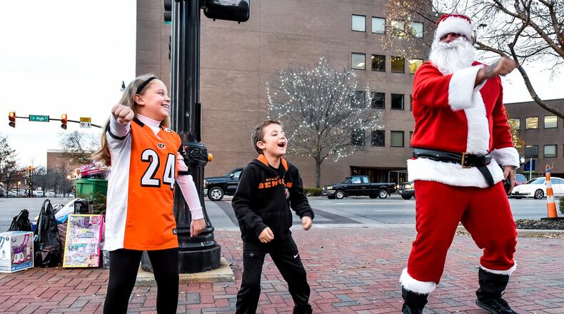 John Drury, dressed up as Santa, dances with local children as he collects toys Wednesday for those in need in front of the historic Butler County Courthouse on High Street in Hamilton. NICK GRAHAM/STAFF