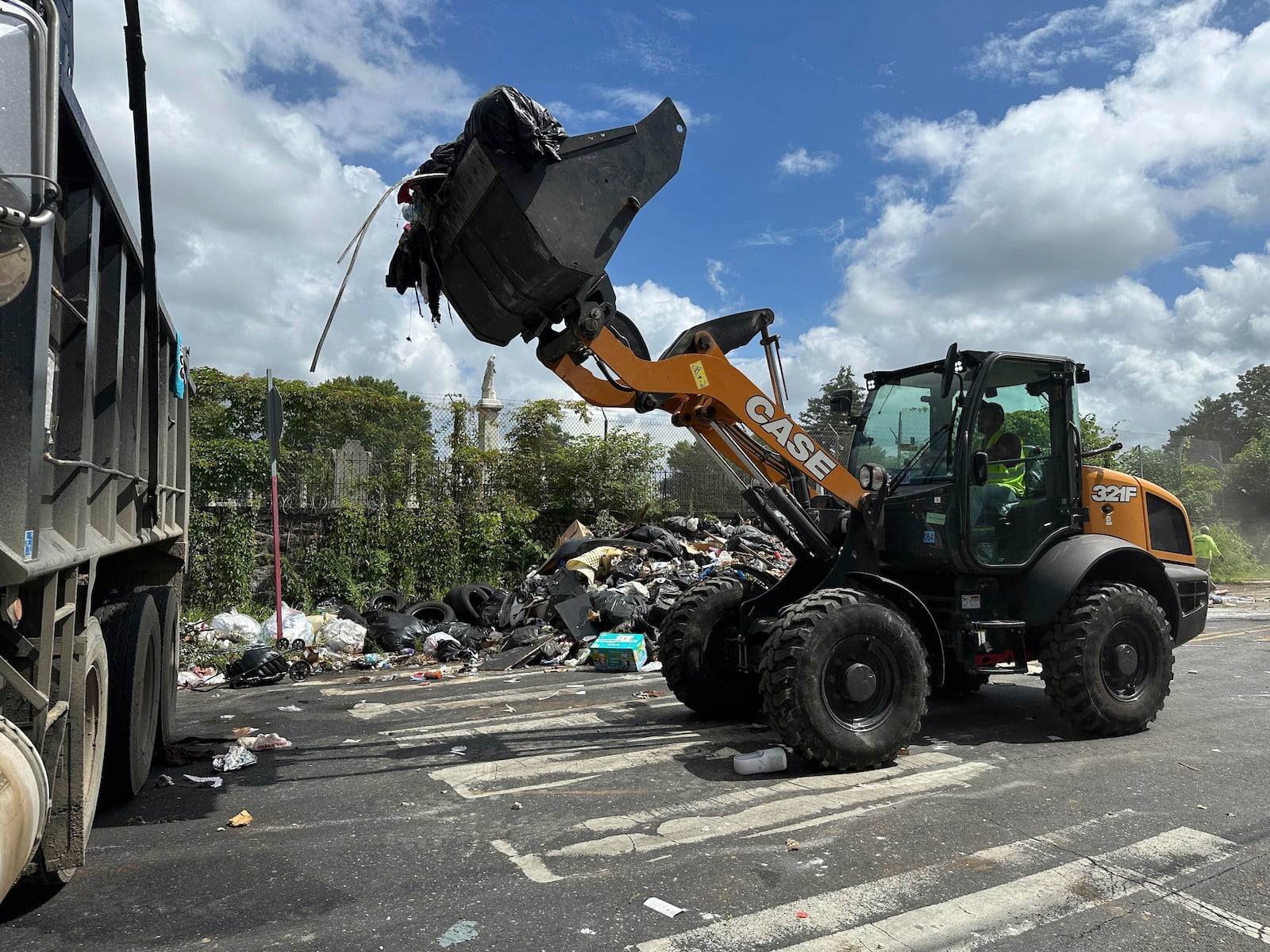 Trash is cleaned up at a drop-off site in Philadelphia as thousands of city workers remained on strike Monday, July 7, 2025. (AP Photo/Tassanee Vejpongsa)