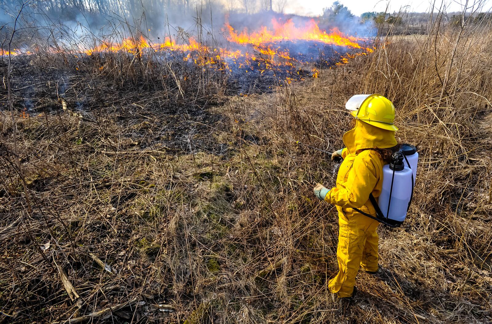 Kathy Schwable makes sure fire doesn't spread as they do a controlled burn at Riverside Natural Area Thursday, Feb. 20, 2020 - a year ago Saturday (notice what the weather looked like then) on Conservation Way in Hamilton. The Hamilton Conservation Corps performed the controlled burns at the Riverside Natural Area to eradicate invasive plant species from the prairie. NICK GRAHAM / STAFF