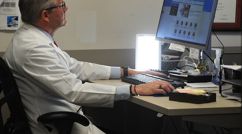 Dr. Mark Williams keeps a Happy Light in his office at the Premier Health Primary Care-Beavercreek. The light helps to battle seasonal affective disorder, a type of depression that occurs this time of year. MARSHALL GORBY\STAFF