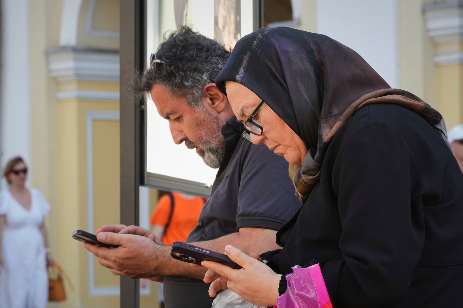 Pedestrians pause to look at their phones in St. Petersburg, Russia, on Monday, July 14, 2025. (AP Photo/Dmitri Lovetsky)