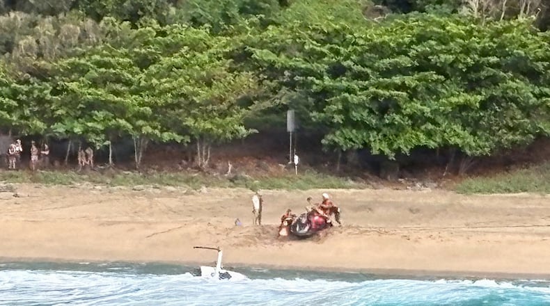 Kauai Ocean Safety members and other people assist individuals after an Airborne Aviation tourist helicopter crash on Kalalau Beach on Kauai, Hawaii, on March 26, 2026. (Petty Officer 2nd Class Tyler Robertson/Station Kauai/U.S. Coast Guard via AP)