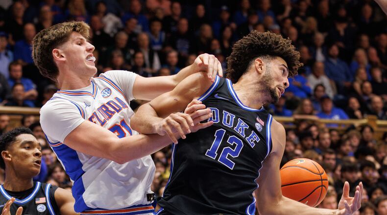 Duke's Cameron Boozer (12) and Floida's Alex Condon (21) battle for a loose ball during the first half of an NCAA college basketball game in Durham, N.C., Tuesday, Dec. 2, 2025. (AP Photo/Ben McKeown)