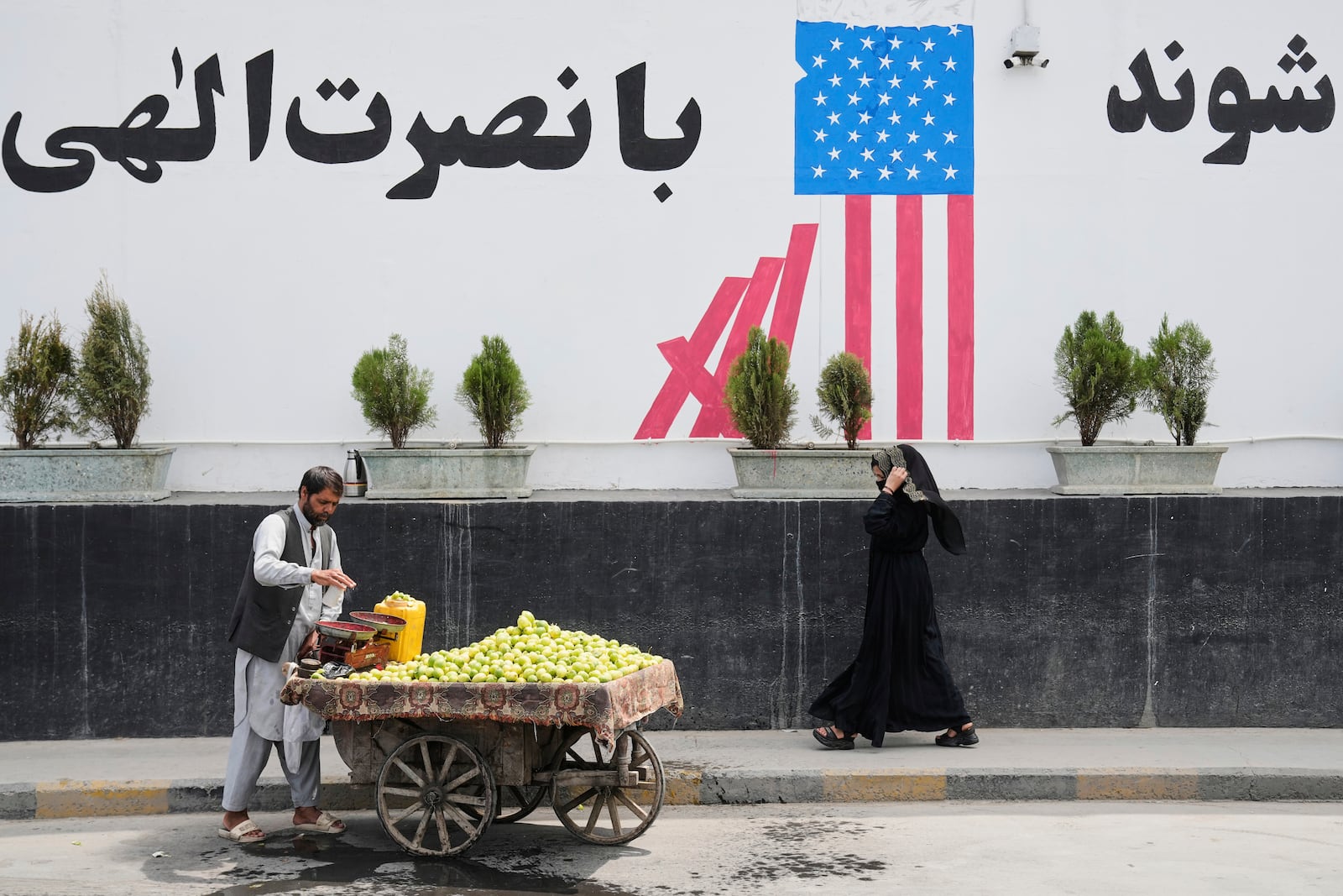 A vendor waits for customers in front of the former US embassy in Kabul, Afghanistan, Thursday, June 5, 2025. (AP Photo/Ebrahim Noroozi)