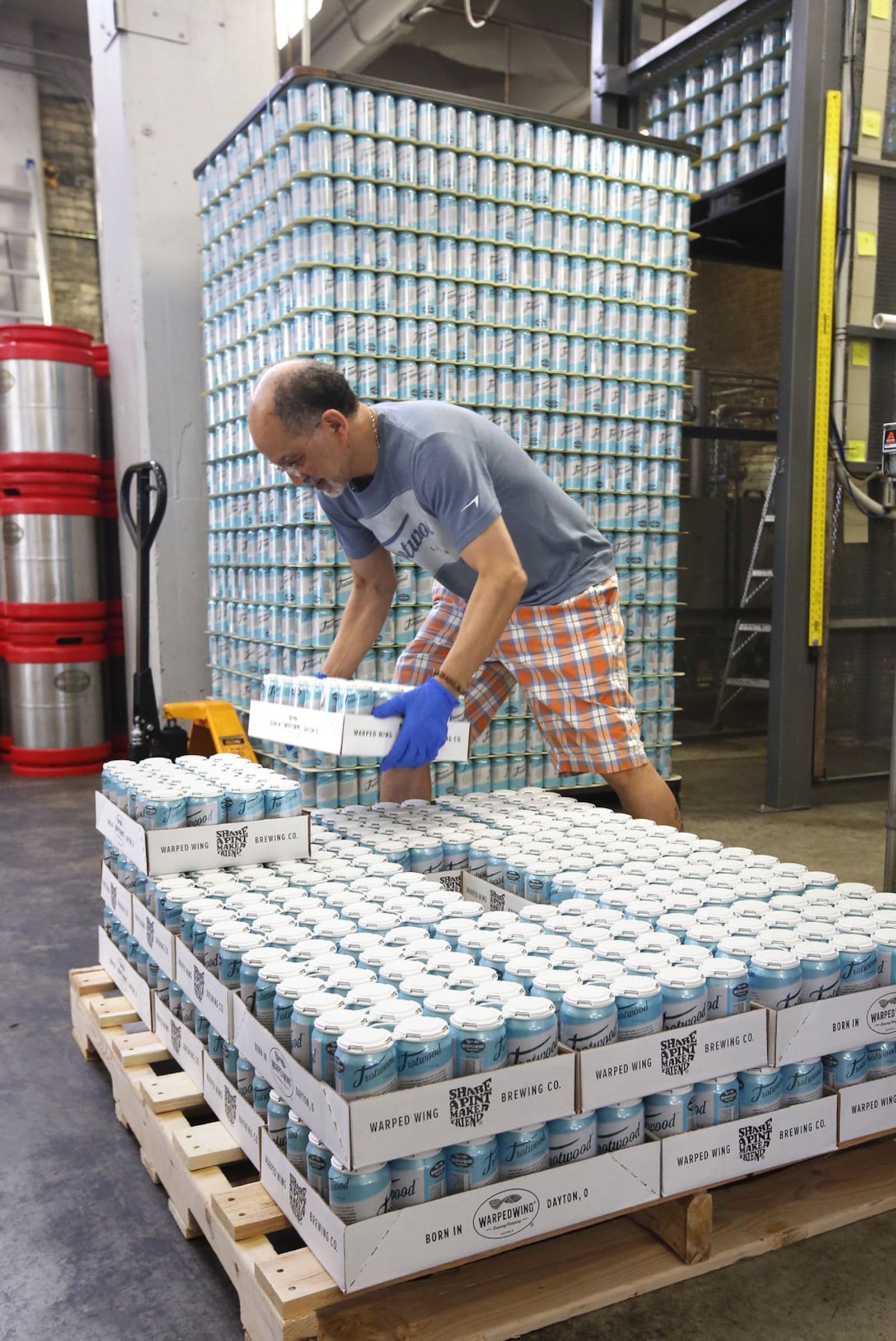 Lahaun Spencer stacks a case of Trotwood Lager at Warped Wing Brewing Company in Dayton. TY GREENLEES / STAFF