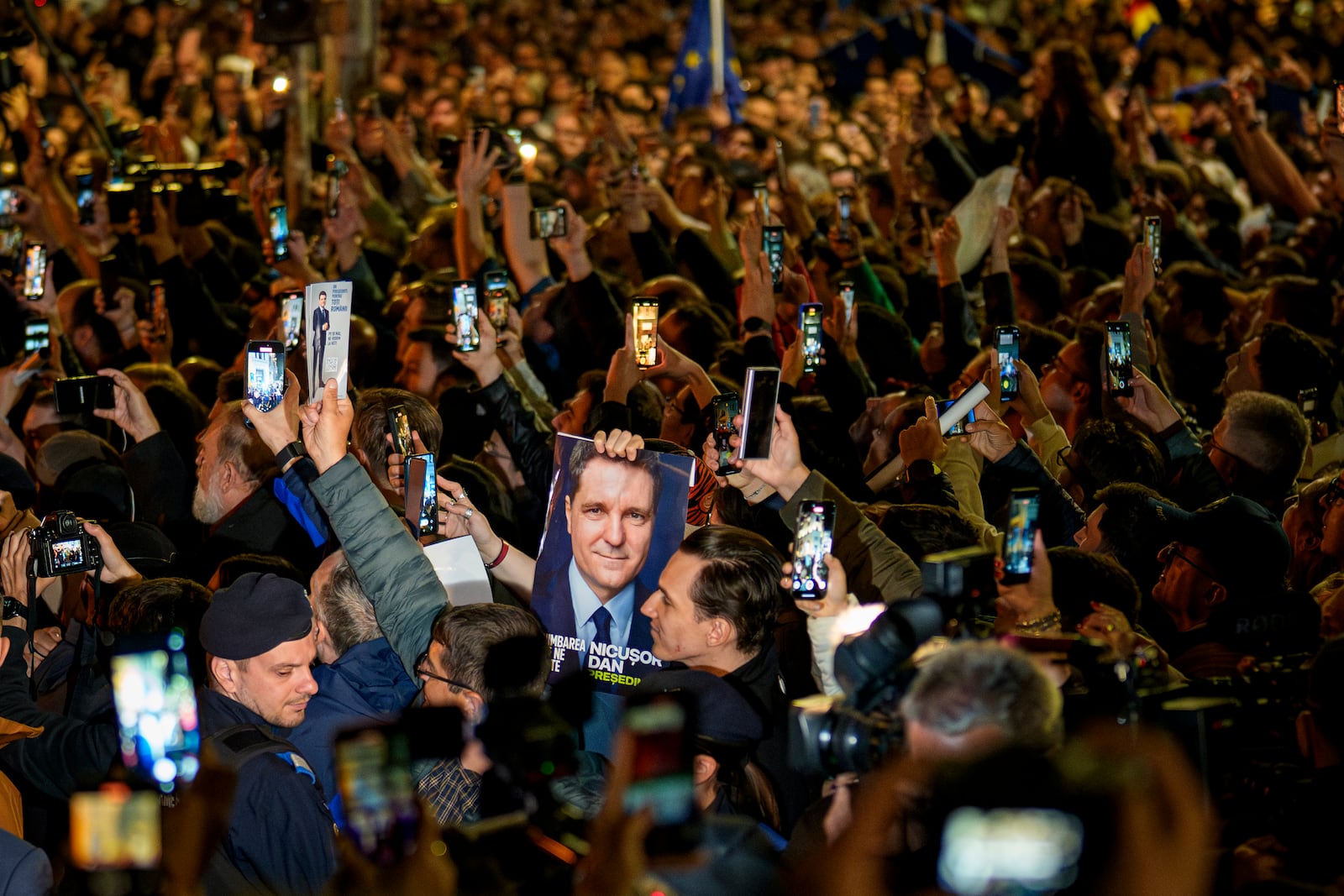 Supporters of presidential candidate Nicusor Dan cheer holding an electoral poster after he won the second round of the country's presidential election redo in Bucharest, Romania, early Monday, May 19, 2025. (AP Photo/Andreea Alexandru)
