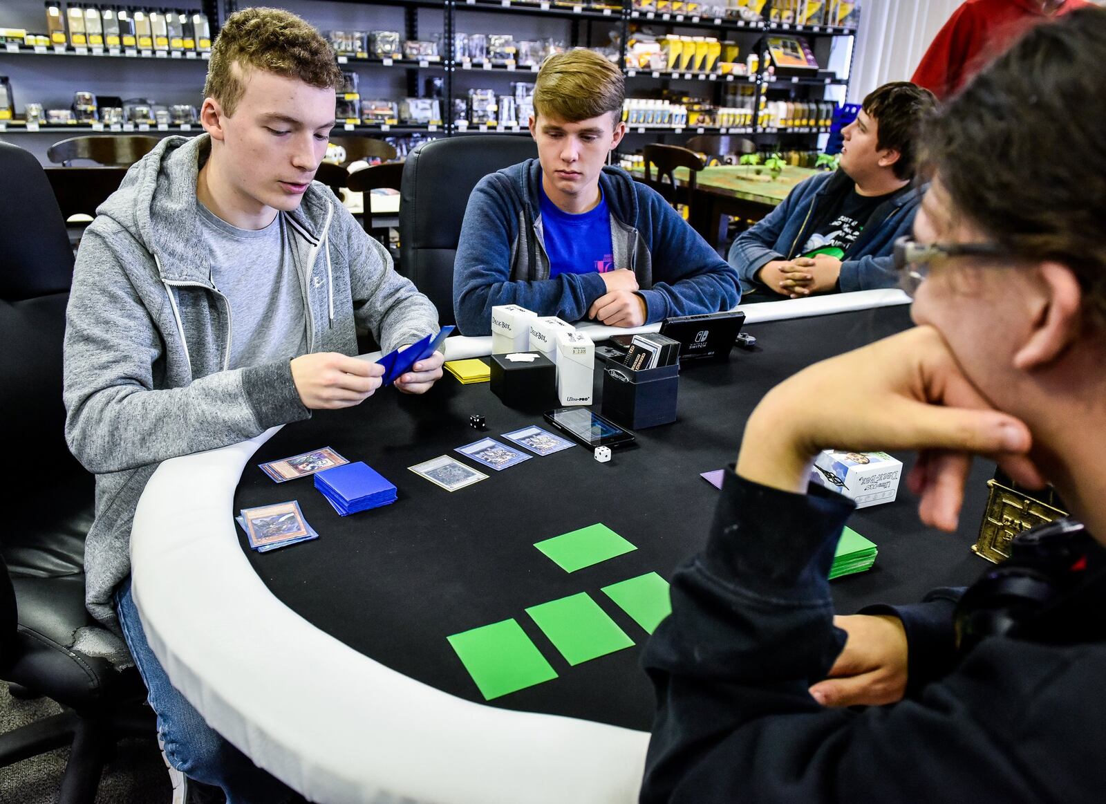 Joshua Grey, 17, left, Hagen Taulbee, 16, middle, and Michael Smith, 16, play Yu-Gi-Oh! at Aurora Distributing Gaming & Hobbies on Brookwood Avenue in Hamilton Wednesday, Nov. 1., 2017. The shop has area for tabletop game play and carries supplies for tabletop gaming, pinewood derby, a large selection of dice, model railroad structures, hobby paint supplies and more. NICK GRAHAM/STAFF