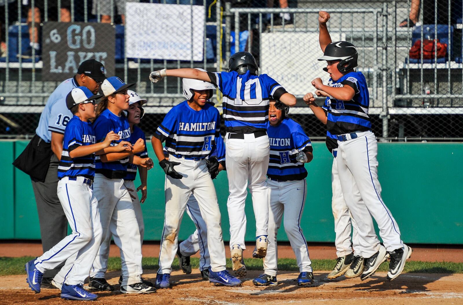 Hamilton West Side’s Jared Halupnik is greeted by teammates at home plate after hitting a two-run home run during their 11-3 loss to Grosse Pointe Woods-Shores (Mich.) on Friday in their Little League Great Lakes Regional at Grand Park Sports Campus in Westfield, Ind. NICK GRAHAM/STAFF