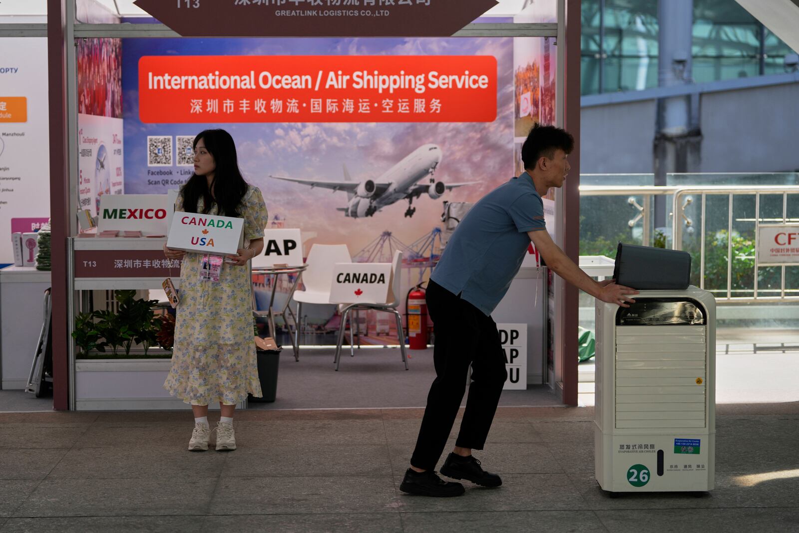 A worker holds up a sign for "Canada USA" in front of a logistics company at the 137th Canton Fair in Guangzhou in southern China's Guangdong province on Tuesday, April 15, 2025. (AP Photo/Ng Han Guan)