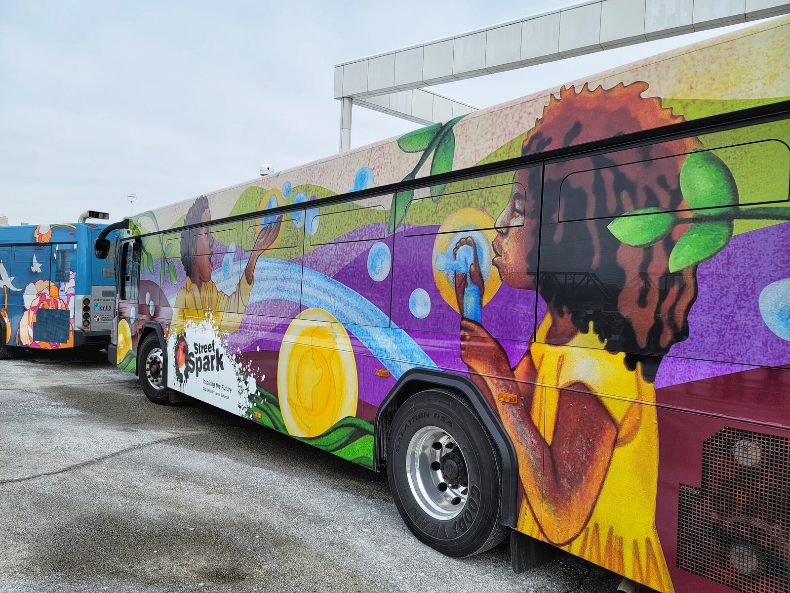 Three Butler County Regional Transit Authority buses have been wrapped in vinyl displaying StreetSpark murals that have been painted around Hamilton. This bus features "Inspiring the Future" mural by artist Jamie Schorsch. That mural is painted on the front of the Booker T. Washington Community Center. NICK GRAHAM / STAFF